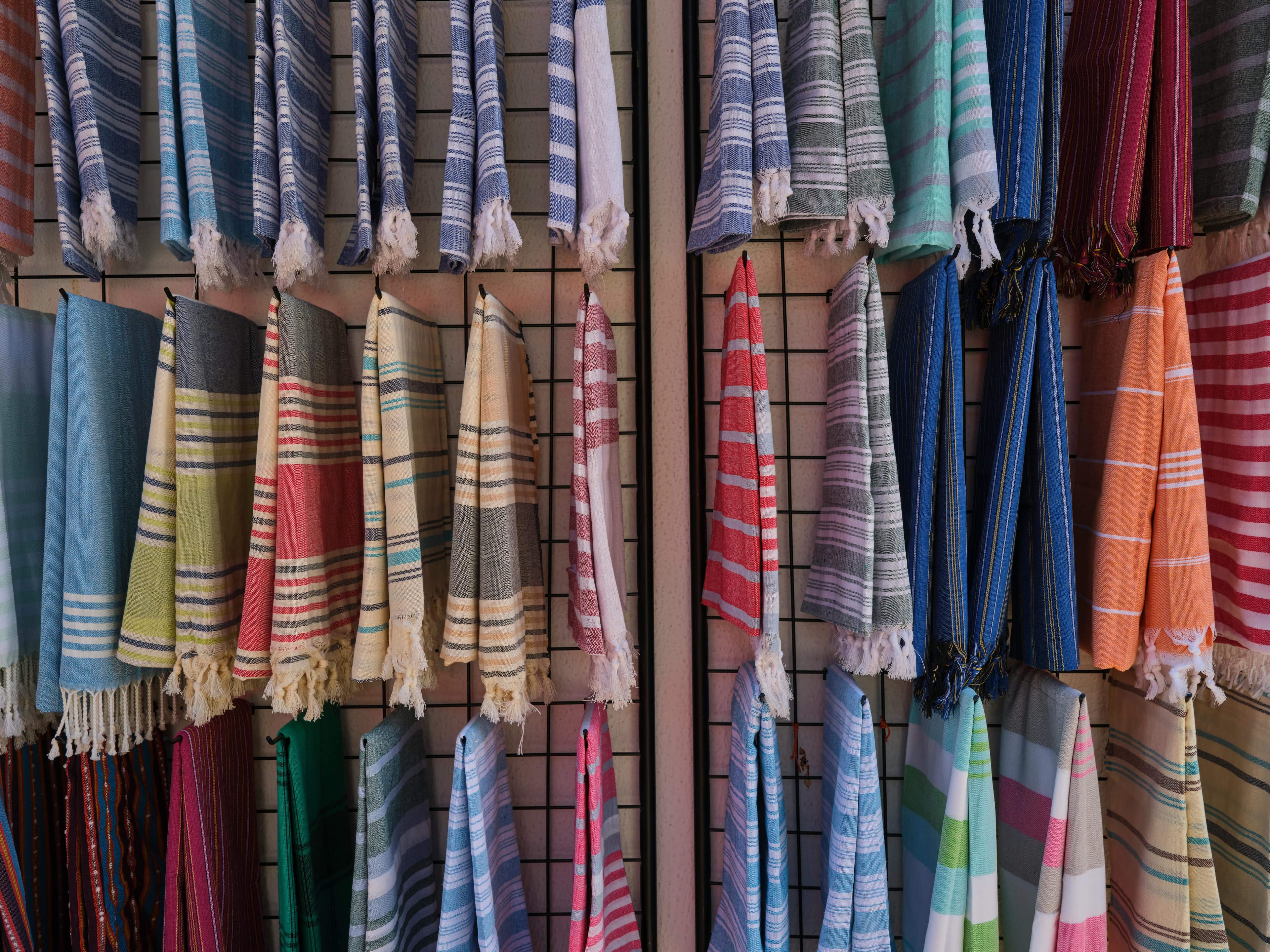 A collection of colorful striped fabrics hanging for sale. Perfect for textile and design enthusiasts.