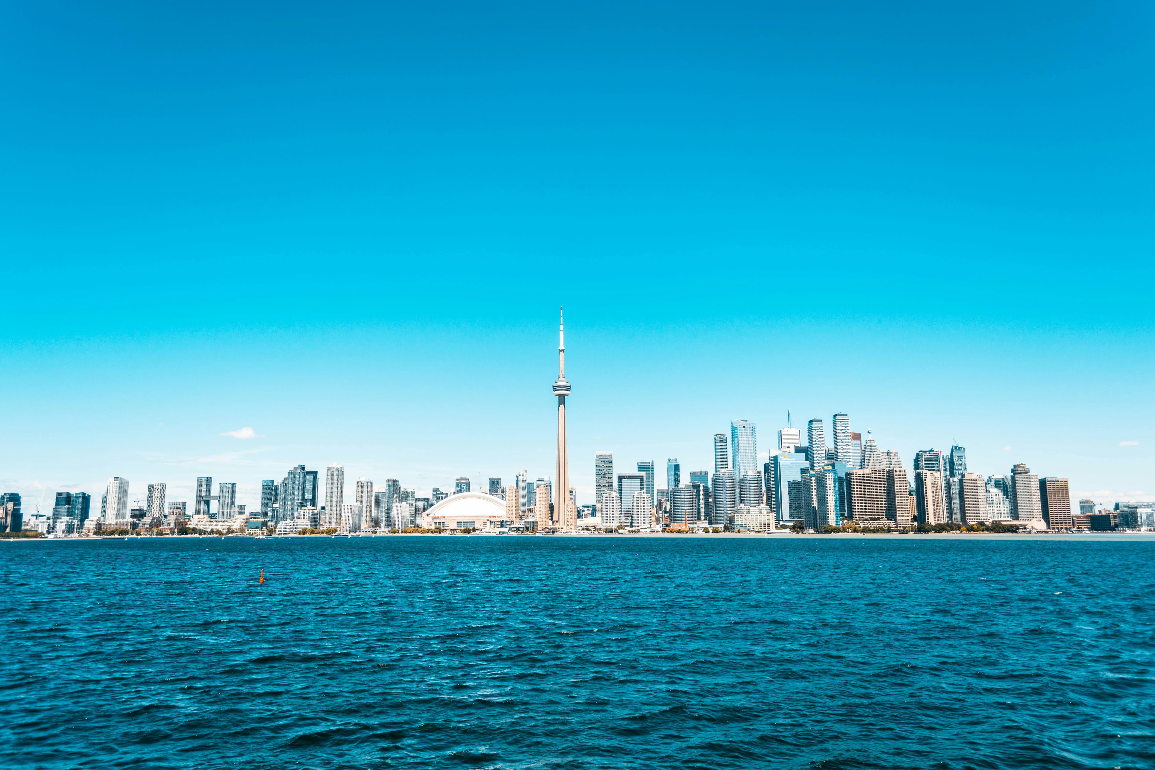 Beautiful view of Toronto skyline featuring the iconic CN Tower and vibrant blue waterfront.