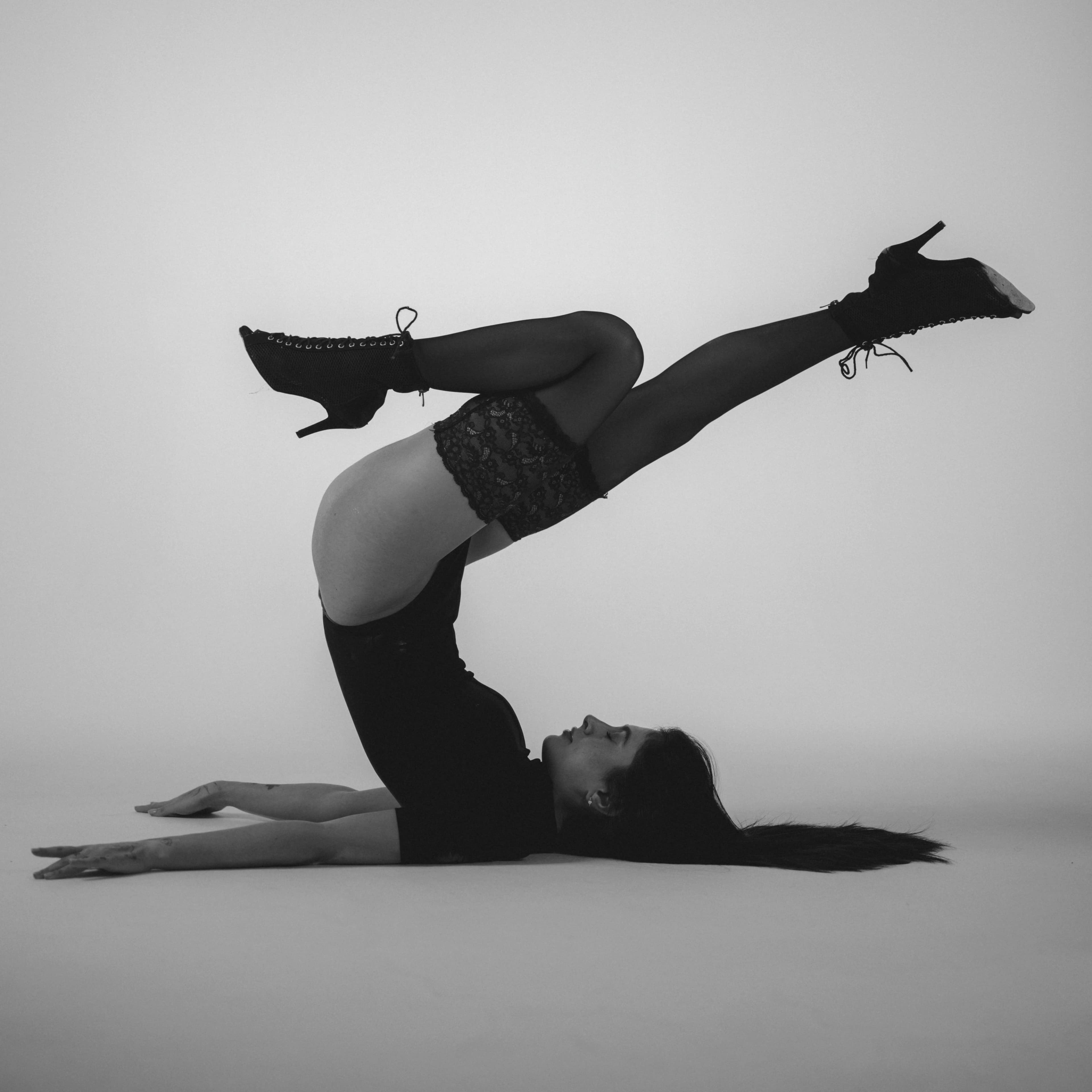 Künstlerisches Schwarzweißfoto einer Frau in einer Kontorsion-Pose, die Eleganz und Stärke zur Schau stellt.