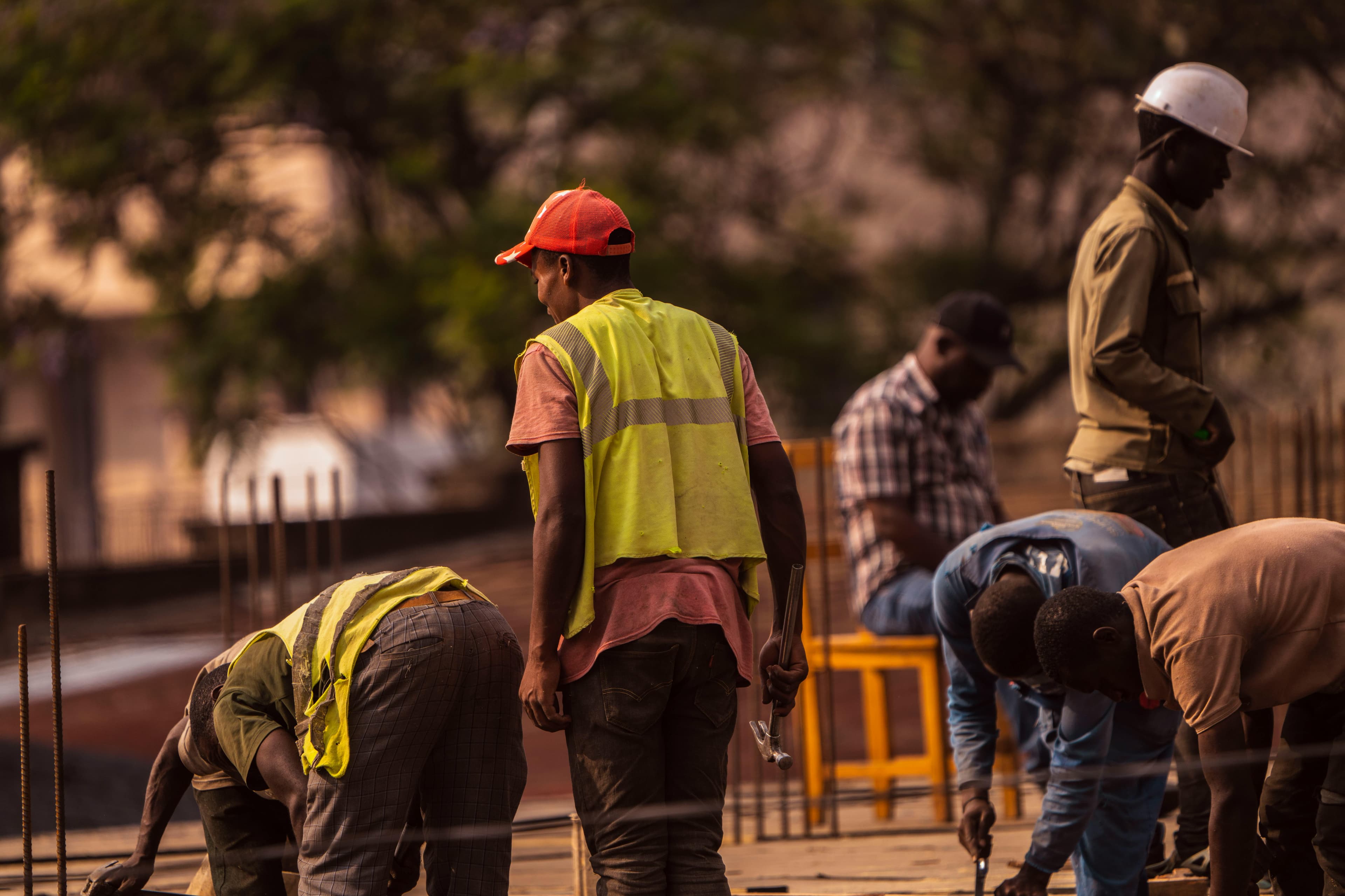 Groupe d'ouvriers du bâtiment masculins sur le chantier portant un équipement de sécurité pendant la journée.