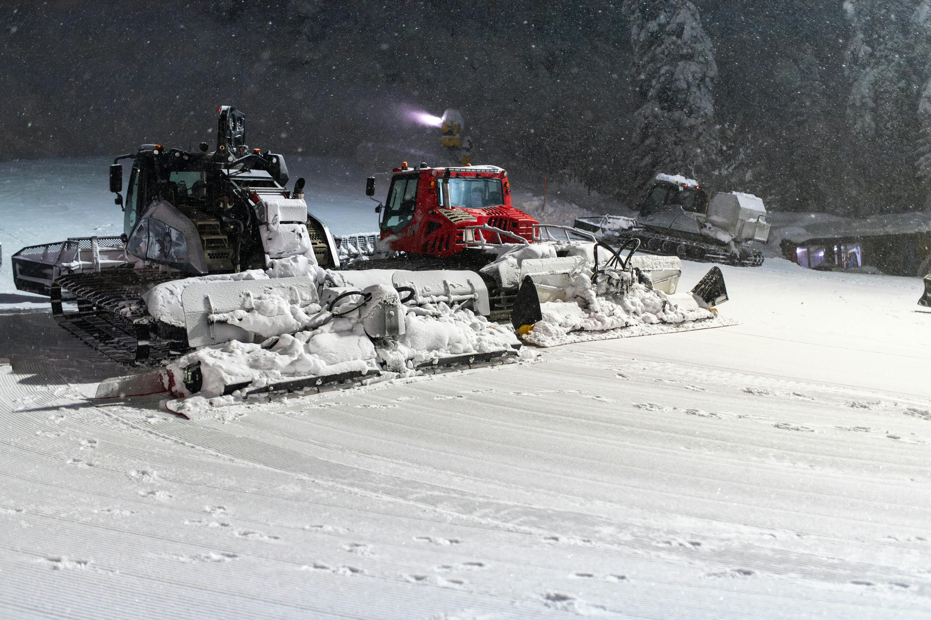 スノーキャットが雪の斜面を整備し、ウィンタースポーツの地形を美しくする夜景。
