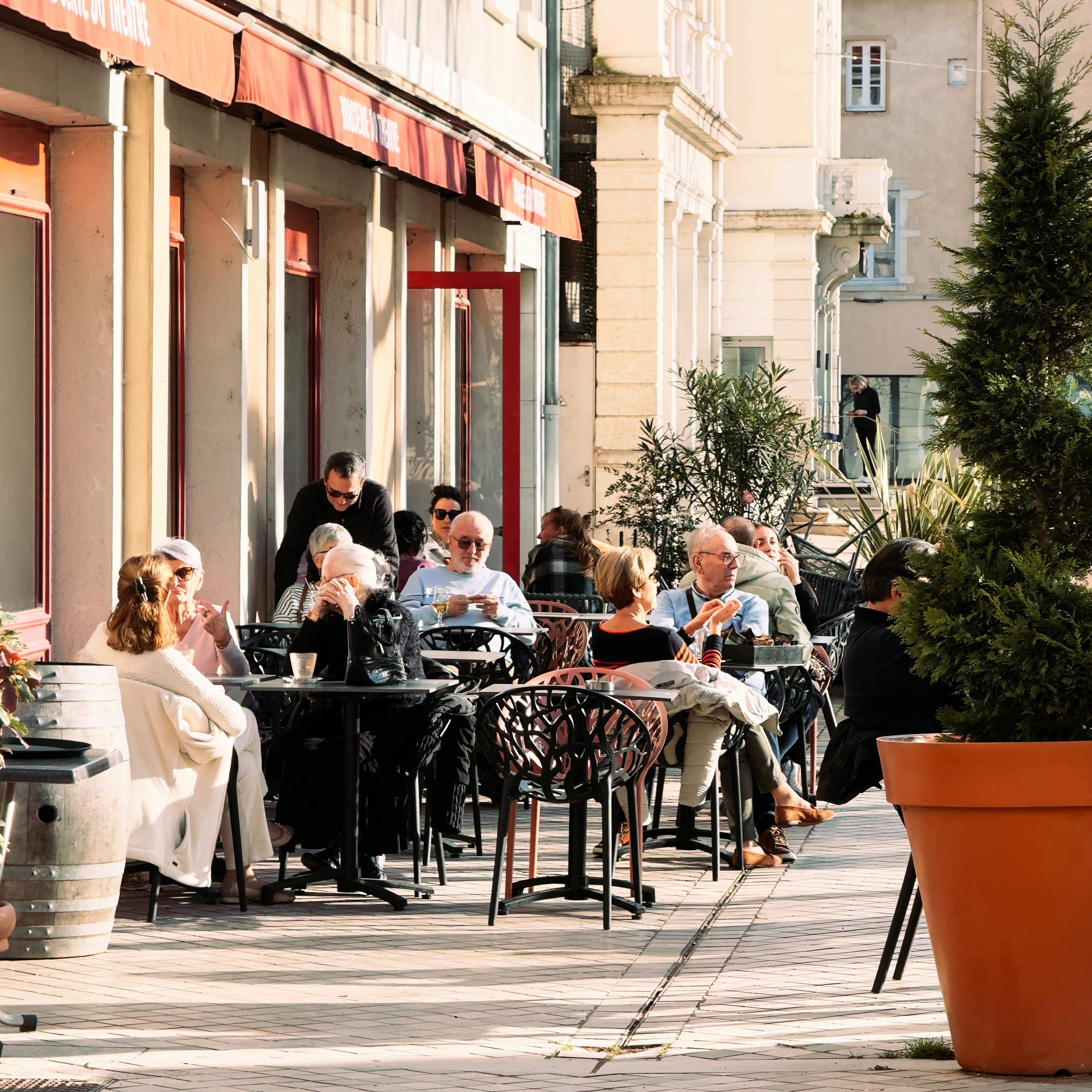 Aproveite um dia ensolarado em um movimentado café ao ar livre em Villefranche-sur-Saône, França, com clientes descontraídos.