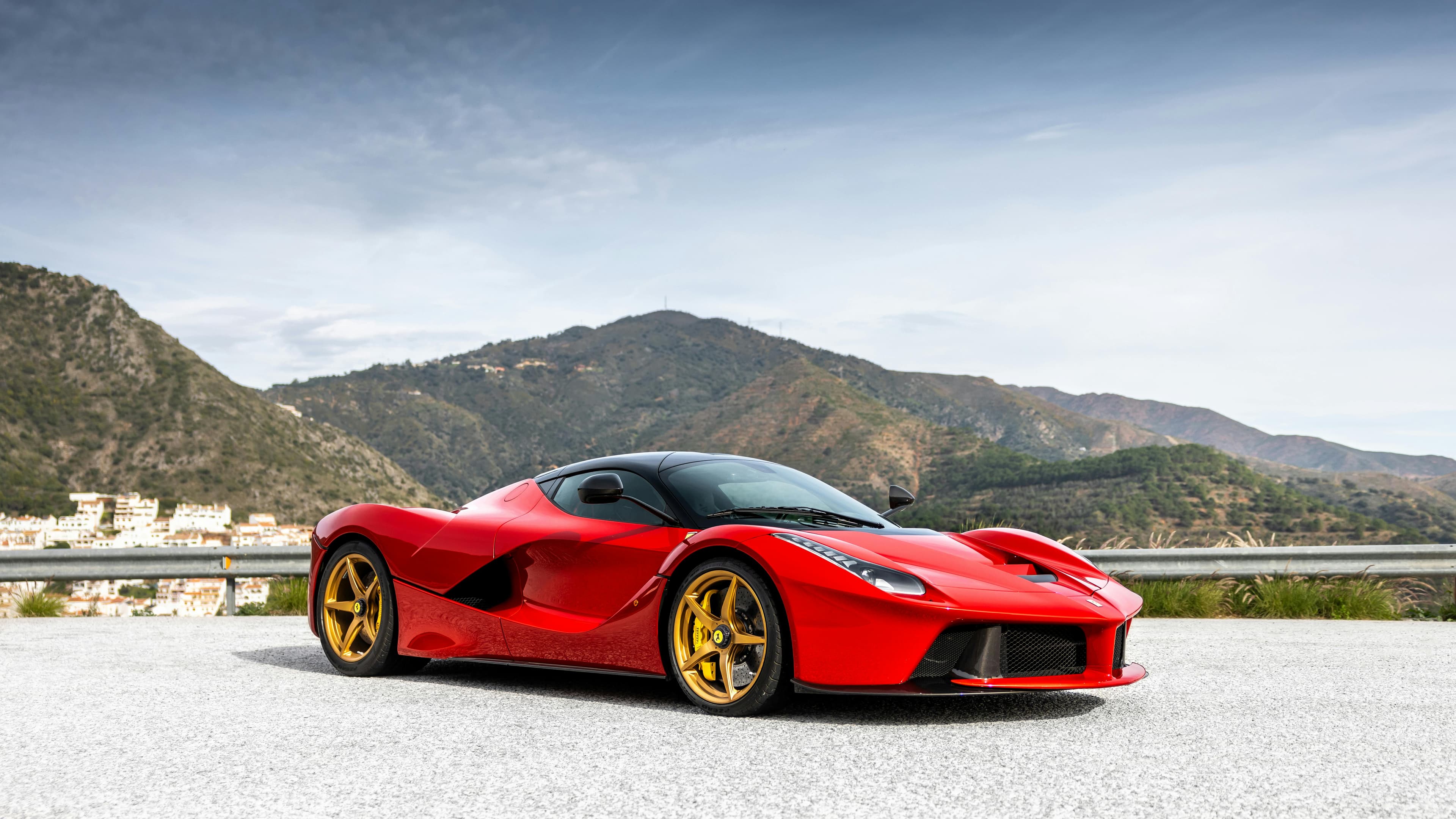 Un elegante coche deportivo rojo aparcado en una carretera de montaña con un impresionante telón de fondo.