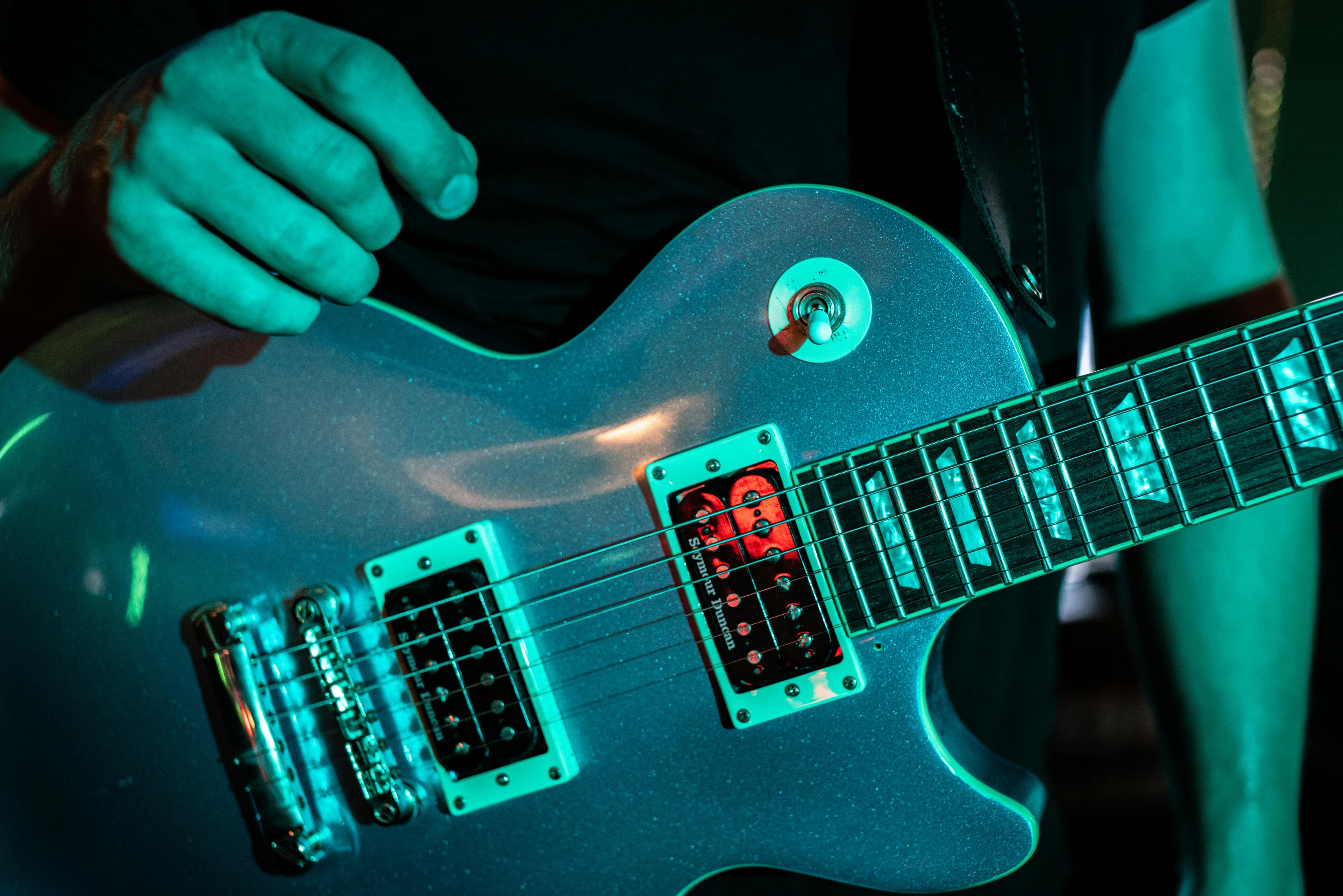 Close-up van de hand van een muzikant die een elektrische gitaar bespeelt op een livemuzieklocatie in Winston-Salem, North Carolina.