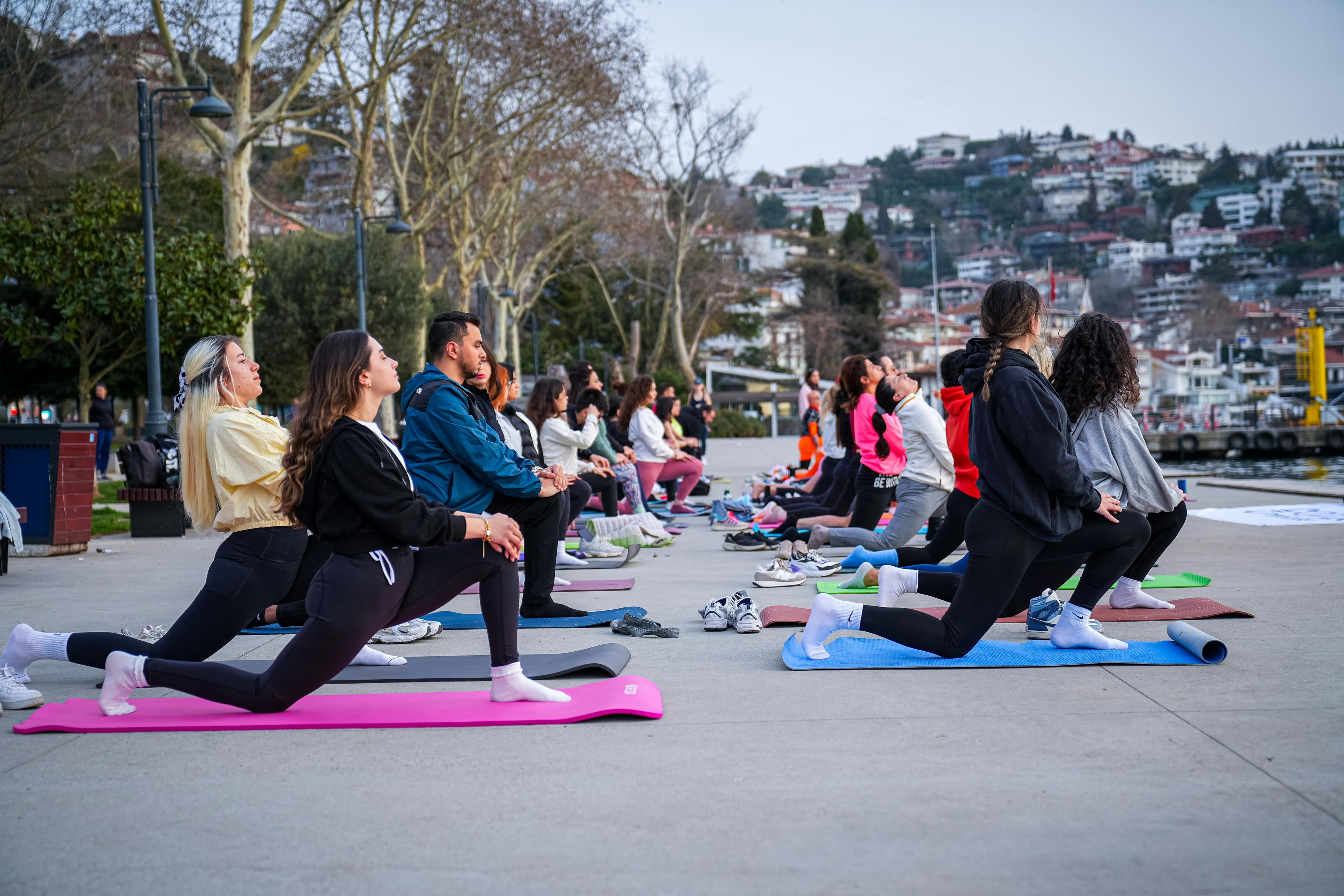 Grupo practicando yoga en el paseo marítimo de Estambul, mostrando fitness y armonía.