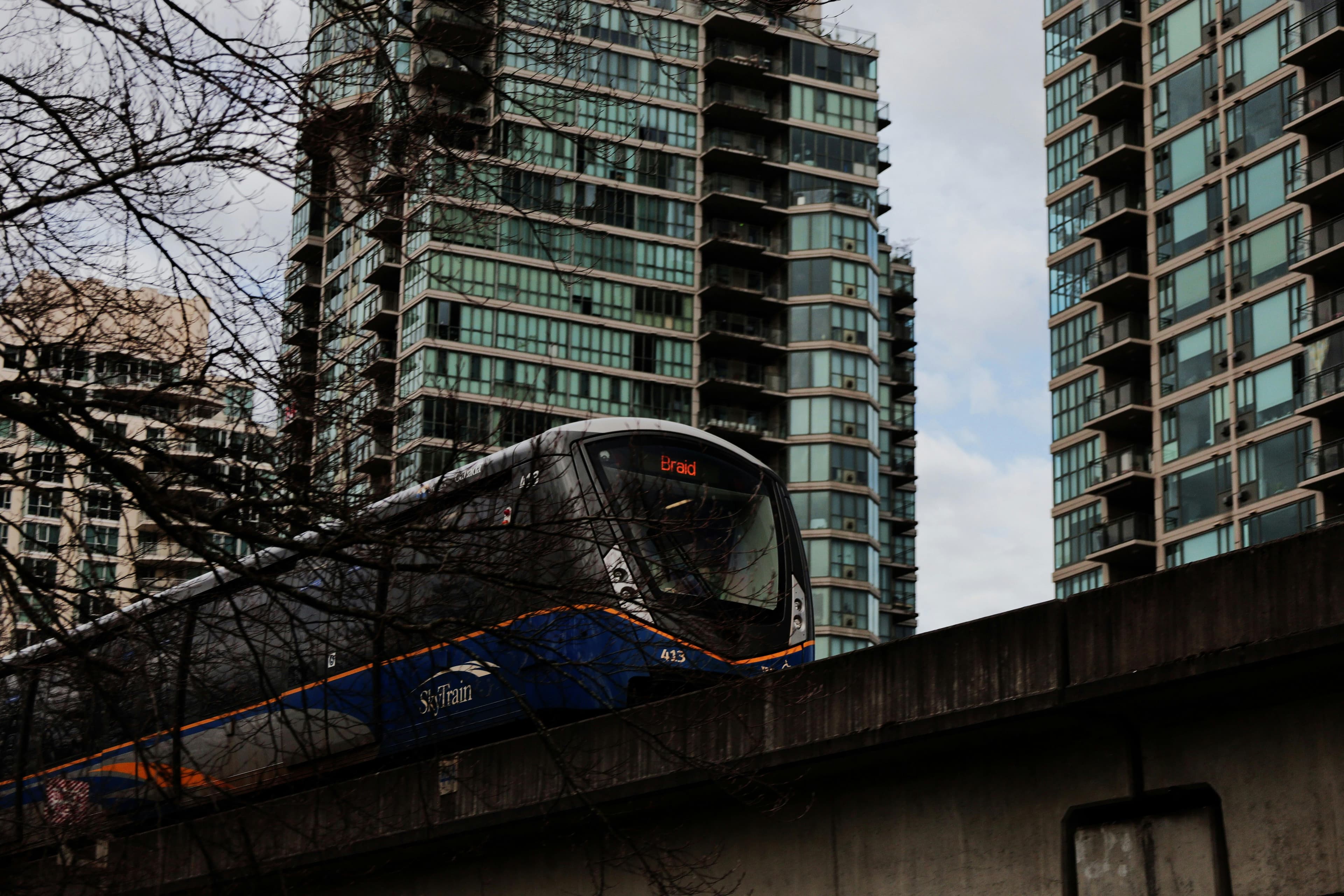 Lo SkyTrain passa accanto ai moderni grattacieli di Vancouver, sottolineando l'importanza del trasporto urbano e dell'architettura.
