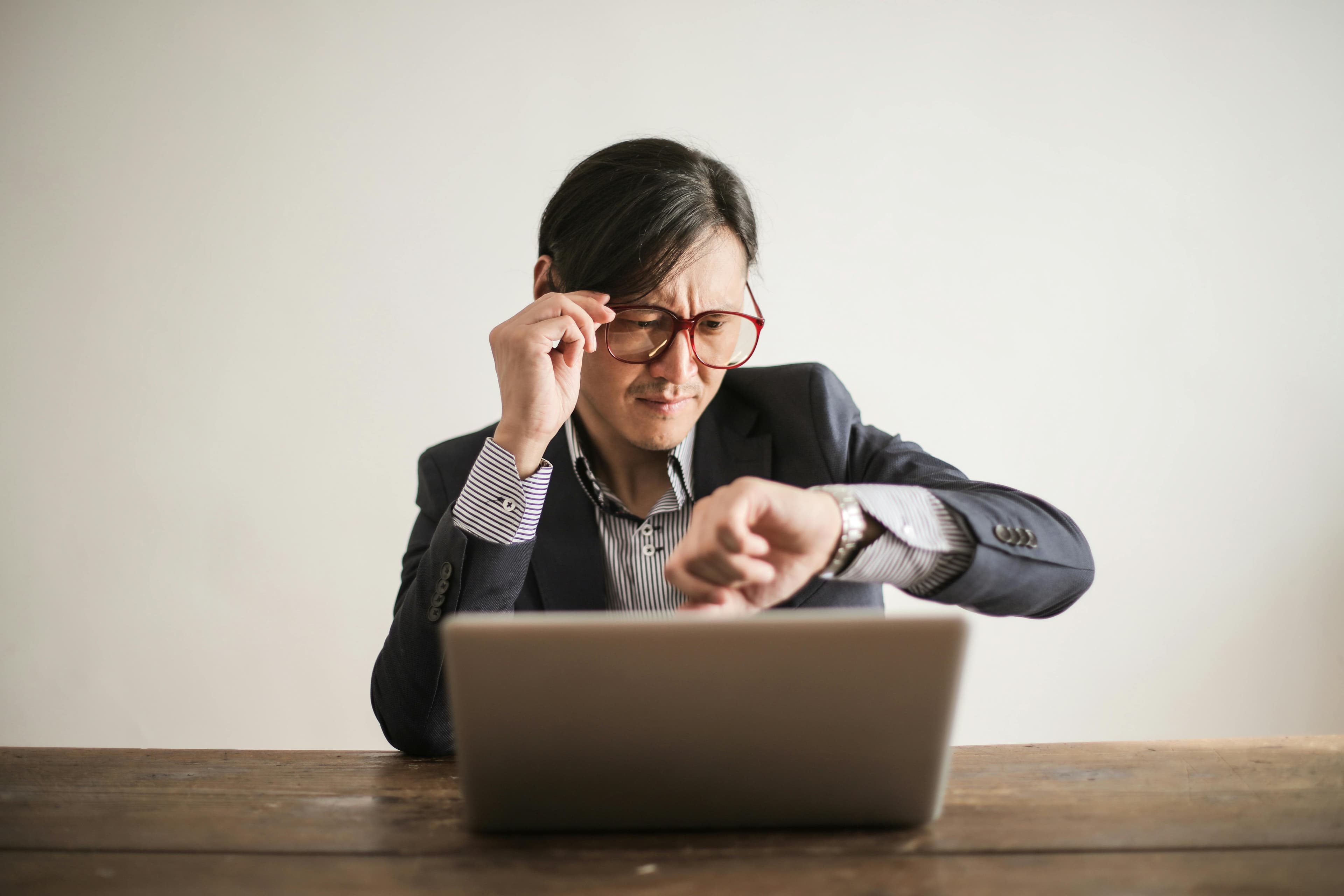 困惑的商人，检查在手表上的时间