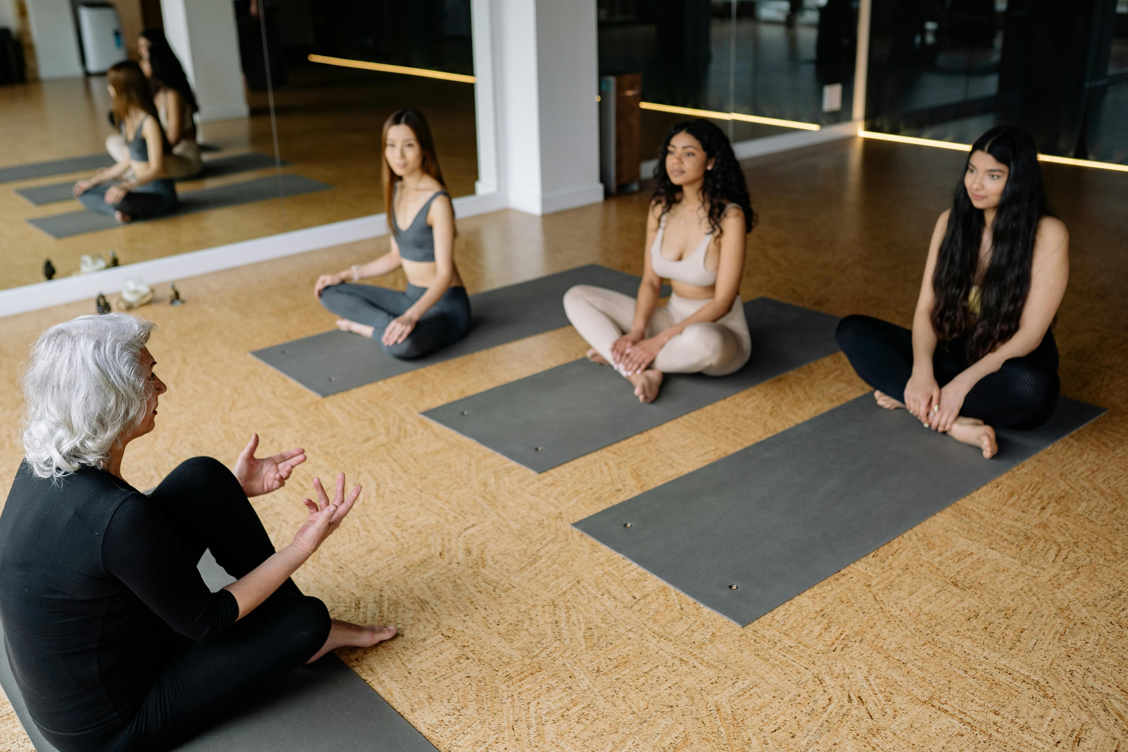 A yoga instructor guides three young women in a relaxing yoga session inside a studio.